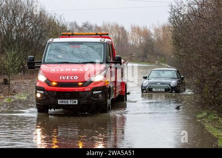 Allerton Bywater, Castleford, Regno Unito. 2 gennaio 2024. Un furgone di recupero autostradale tira un'auto bloccata sulla strada allagata causata da tempeste e forti piogge nei pressi di Leeds su Newton Lane, Fairburn, Castleford, Regno Unito, 2 gennaio 2024 (foto di James Heaton/News Images) ad Allerton Bywater, Castleford, Regno Unito il 1/2/2024. (Foto di James Heaton/News Images/Sipa USA) credito: SIPA USA/Alamy Live News Foto Stock