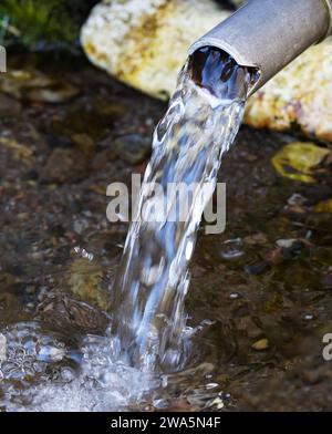 Acqua dolce che fuoriesce da un tubo. Immagine che illustra la scarsità d'acqua e l'importanza dell'acqua pulita fresca nell'ambiente. Foto Stock