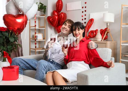 Giovane coppia con un bicchiere di vino seduto a casa il giorno di San Valentino Foto Stock