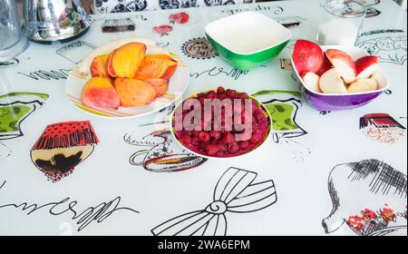 banane pesche mele e lamponi su un piatto sul tavolo Foto Stock