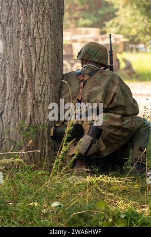 Ricostruzione storica. I soldati tedeschi della Wehrmacht durante la seconda guerra mondiale combattono nella foresta. Vista dal retro Foto Stock