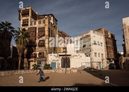 Uomo che cammina davanti agli edifici alti di al Balad, quartiere storico di Jeddah, Arabia Saudita Foto Stock