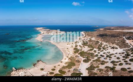 Isola di Creta, laguna di Elafonisi, Grecia. Vista aerea con droni dell'acqua di mare trasparente turchese, barca ormeggiata, cielo blu, spiaggia con sabbia rosa. Foto Stock