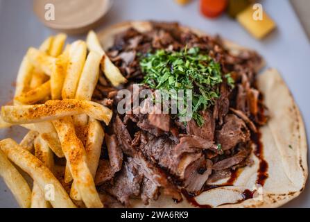 Doner Kebab su piatto con patatine fritte e carne alla griglia su piatto. Carne fritta con patatine fritte. Shawarma con manzo alla griglia e insalata. Foto Stock