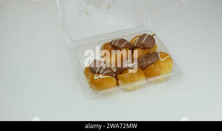 Una foto ravvicinata dei profiteroles di cioccolato in una scatola di plastica. Foto Stock