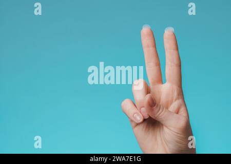 Primo piano cerotto acne rotondo sul dito su sfondo blu. Macchie di acne per il trattamento del brufolo e della rosacea da vicino. Pulizia viso ringiovanente cosme Foto Stock