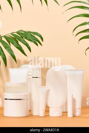 Tubi in plastica bianca, vasetti su sfondo beige, contenitori per creme e gel cosmetici, pubblicità e promozione del marchio Foto Stock