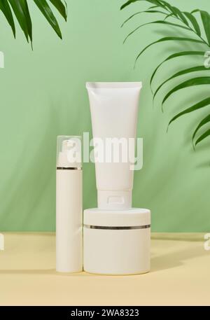 Tubi in plastica bianca, vasetti su sfondo verde, contenitori per creme e gel cosmetici, pubblicità e promozione del marchio Foto Stock