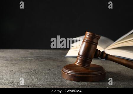 Concetto di legge. Gavel e libro su tavolo con texture grigie su sfondo nero, spazio per il testo Foto Stock