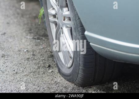 Ruota con pneumatico quasi piatto sul lato della strada. Foto Stock