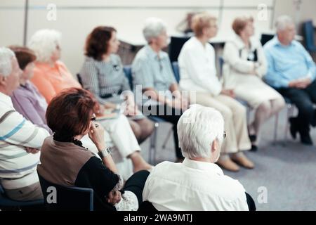 Vista posteriore di un anziano che ascolta una lezione Foto Stock