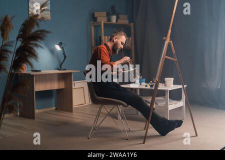 Artista attraente che dipinge pittura creativa in un'atmosfera autentica con vista sul lato casa Foto Stock