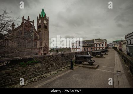 Vista dalle mura della città di Derry o Londonderry, luogo con i cannoni, che si affaccia sulla piazza della città con Guildhall sullo sfondo. Foto Stock