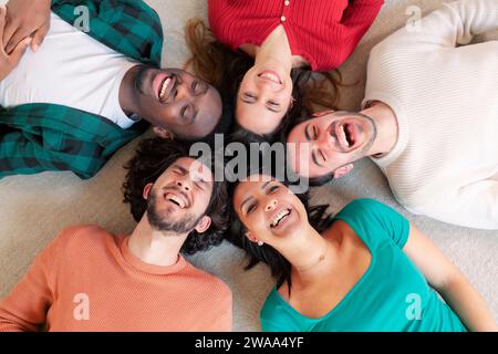 Amici multiculturali che scattano foto di selfie con lo smartphone in cerchio sul pavimento - felici giovani sorridenti insieme alla fotocamera Foto Stock