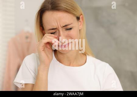 Donna triste con mascara puzzolente che piange in casa Foto Stock