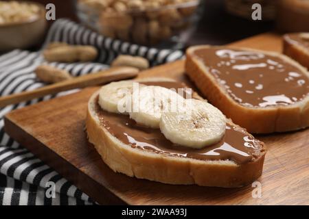 Tosta con gustoso burro di noci e fette di banana su tavola di legno, primo piano Foto Stock