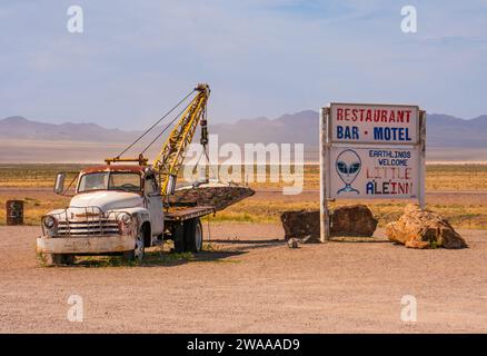 L'indicazione per il motel vicino all'area 51 di Little A'le'inn, sulla statale 375, a Rachel, Nevada. Giornata di sole nebulosa. Rusty Truck, paesaggio desertico asciutto. Foto Stock