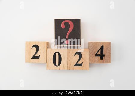 Numero 2024 e punto interrogativo scritto su blocchi di legno isolati su sfondo bianco. Foto Stock