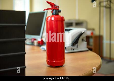 Estintore in ufficio sul posto di lavoro contro la pianura sfondo neutro Foto Stock