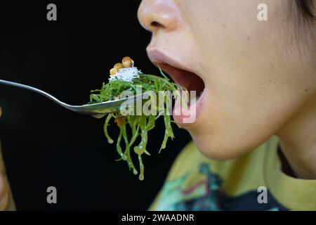 Nusa Penida, Bali-4 settembre 2021: Una foto ravvicinata della bocca mangia le alghe su un cucchiaio. A Bali, si chiama bulung Foto Stock