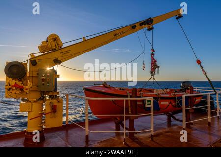 Nave di salvataggio arancione su una grande nave da carico e gru. Trapano uomo a bordo. Addestramento in scialuppa di salvataggio. Foto Stock