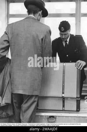 Passare la dogana negli anni '1950 Un uomo che arriva all'aeroporto di Bromma e viene visto guardare un ufficiale della dogana che guarda attraverso i suoi bagagli e apre per vedere cosa c'è dentro. 1955. Foto Stock