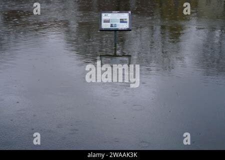 Lubeck, Germania. 3 gennaio 2024, Schleswig-Holstein, Lübeck: Un cartello sulle rive dell'Eco City Trail si trova al centro del fiume Trave. Sezioni della trave hanno già fatto esplodere le loro banche. La città anseatica di Lübeck ha avvertito del pericolo di inondazioni in alcune parti del centro città mercoledì. Secondo le previsioni, il livello dell'acqua dovrebbe raggiungere un'altezza di 1,05 metri sul livello del mare intorno alle 11,00, come annunciato dalla città. Foto: Marcus Brandt/dpa credito: dpa Picture Alliance/Alamy Live News Foto Stock