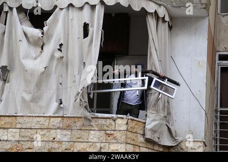 Beirut, Libano. 3 gennaio 2024. Un uomo libanese lancia ha distrutto gli effetti personali del suo appartamento parzialmente distrutto che è stato colpito nell'attacco israeliano all'ufficio di Hamas il 2 gennaio, uccidendo il leader di Hamas Saleh al-Arouri e altri sei nel sobborgo meridionale di Beirut. Crediti: Marwan Naamnai/dpa/Alamy Live News Foto Stock