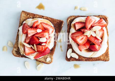 Piatto di brindisi per colazione con ricotta, fragole e mandorle su fondo di marmo bianco. Foto Stock