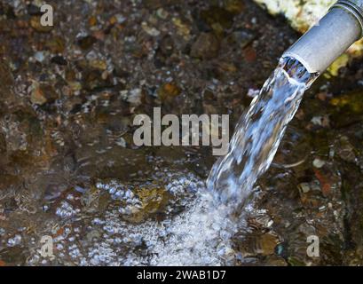 Acqua dolce che fuoriesce da un tubo. Immagine che illustra la scarsità d'acqua e l'importanza dell'acqua pulita fresca nell'ambiente. Foto Stock