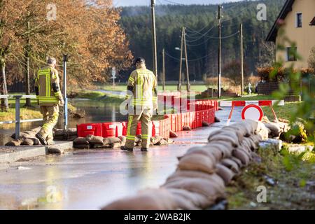 Schleusingen, Germania. 3 gennaio 2024. I vigili del fuoco controllano una diga mobile per proteggere i residenti nel distretto di Rappelsdorf dal fiume Schleuse. Credito: Michael Reichel/dpa/Alamy Live News Foto Stock