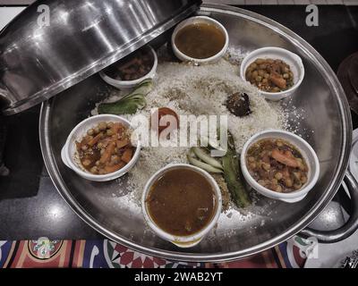 Varie verdure e carne con salsa al curry in padella insieme al riso sul tavolo in un ristorante. Vista dall'alto. Foto Stock