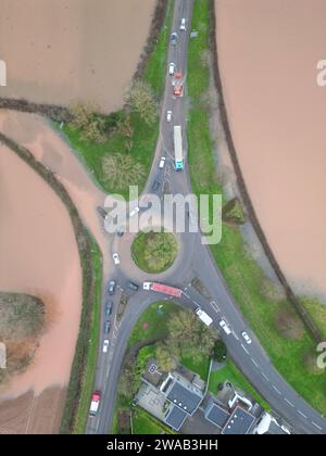 Hereford, Herefordshire, Regno Unito – mercoledì 3 gennaio 2024 – tempo nel Regno Unito – Vista aerea dei campi allagati e delle strade alla periferia di Hereford lungo la strada A4103 per Worcester. Questa inondazione proviene dal fiume Lugg con la strada locale per Sutton St Nicholas chiusa a questa rotatoria a causa delle inondazioni. Foto Steven May / Alamy Live News Foto Stock