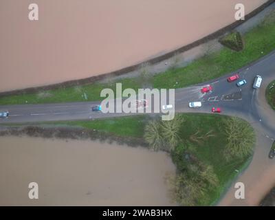 Hereford, Herefordshire, Regno Unito – mercoledì 3 gennaio 2024 – tempo nel Regno Unito – Vista aerea dei campi allagati e delle strade alla periferia di Hereford lungo la strada A4103 per Worcester. Questa inondazione proviene dal fiume Lugg con la strada locale per Sutton St Nicholas chiusa a questa rotatoria a causa delle inondazioni. Foto Steven May / Alamy Live News Foto Stock