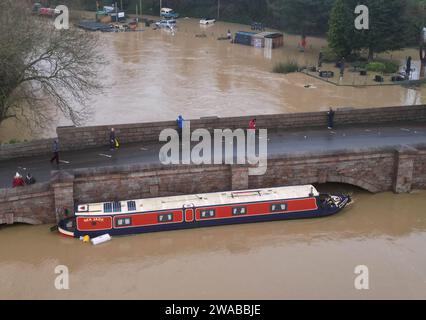 Barrow Upon Soar, Leicestershire, Regno Unito. 3 gennaio 2024. Meteo del Regno Unito. Una barca stretta è intrappolata contro un ponte dopo essersi liberata dal suo ormeggio sul fiume Soar. La pioggia battente ha colpito un'ampia zona del Regno Unito con la piccola ma potente tempesta Henk. Credit Darren Staples/Alamy Live News. Foto Stock