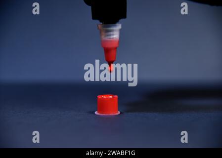 Gocciolamento di inchiostro rosso nel contenitore di plastica. Concetto di arte e design. Primo piano Foto Stock