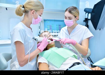 Ortodontista e assistente che raschiano i denti del paziente con lo scanner intraorale 3d in clinica. Concetto di assistenza sanitaria e stomatologia Foto Stock