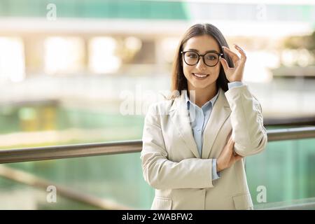 Giovane donna professionale con occhiali sorridenti con sicurezza, vestita Foto Stock
