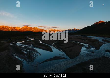 Fiume che conduce alle montagne dorate al sole di mezzanotte in Alaska. Foto Stock