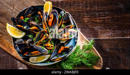 Composizione con un piatto di cozze al vapore servito con prezzemolo e limone Foto Stock