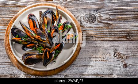 Composizione con un piatto di cozze al vapore servito con prezzemolo e limone Foto Stock