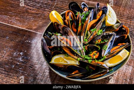 Composizione con un piatto di cozze al vapore servito con prezzemolo e limone Foto Stock