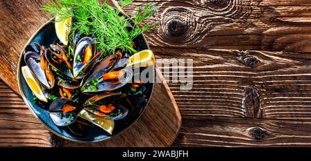 Composizione con un piatto di cozze al vapore servito con prezzemolo e limone Foto Stock