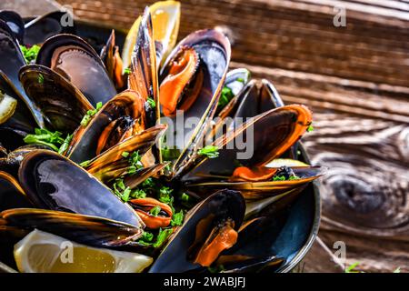 Composizione con un piatto di cozze al vapore servito con prezzemolo e limone Foto Stock