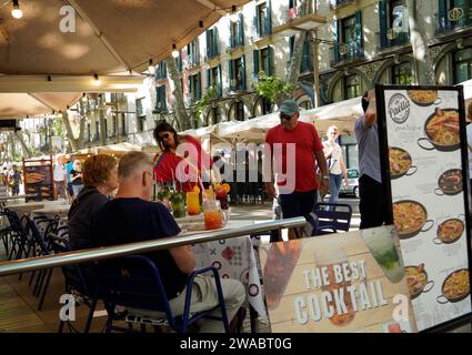 Barcellona, Spagna - 26 maggio 2022: La coppia si prende un drink esotico sulla terrazza di un ristorante sulle Ramblas di Barcellona mentre altri turisti fotografano Foto Stock