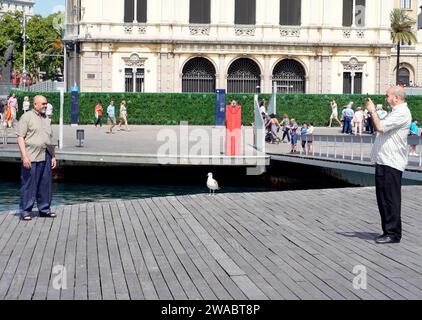 Barcellona, Spagna - 26 maggio 2022: Due gemelli di origine araba vengono fotografati insieme nel porto, tra i due c'è un gabbiano tranquillo e calmo. Foto Stock