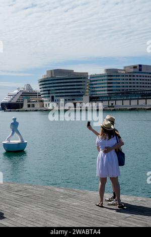 Barcellona, Spagna - 26 maggio 2022: La coppia con cappello estivo prende un autoritratto vicino alla scultura di un uomo che guarda verso le stelle di Robert Llimos i. Foto Stock