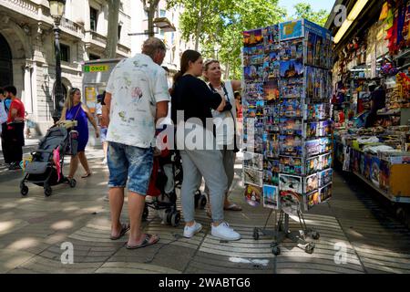 Barcellona, Spagna - 26 maggio 2022: La famiglia di turisti con un passeggino sceglie le cartoline in uno dei locali della Rambla di Barcellona, un traditore Foto Stock