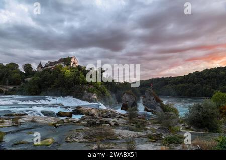 Cascate del Reno - la cascata più grande d'Europa, con il Castello Laufen sulla collina all'ora del tramonto con nuvole drammatiche e tempestose Foto Stock