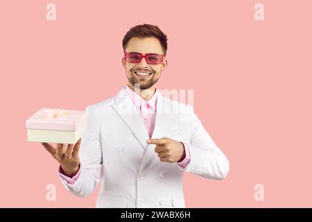 Uomo sorridente in completo saluto con confezione regalo Foto Stock